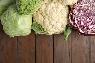 Flat lay composition with different cabbages on wooden background