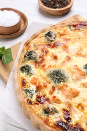 Delicious homemade quiche with salmon and broccoli on white table, closeup