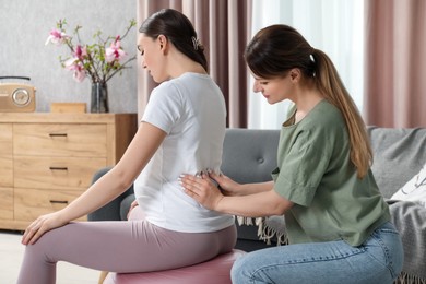 Doula massaging pregnant woman at home. Preparation for child birth