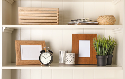 Photo of White shelving unit with photo frames and different decorative elements