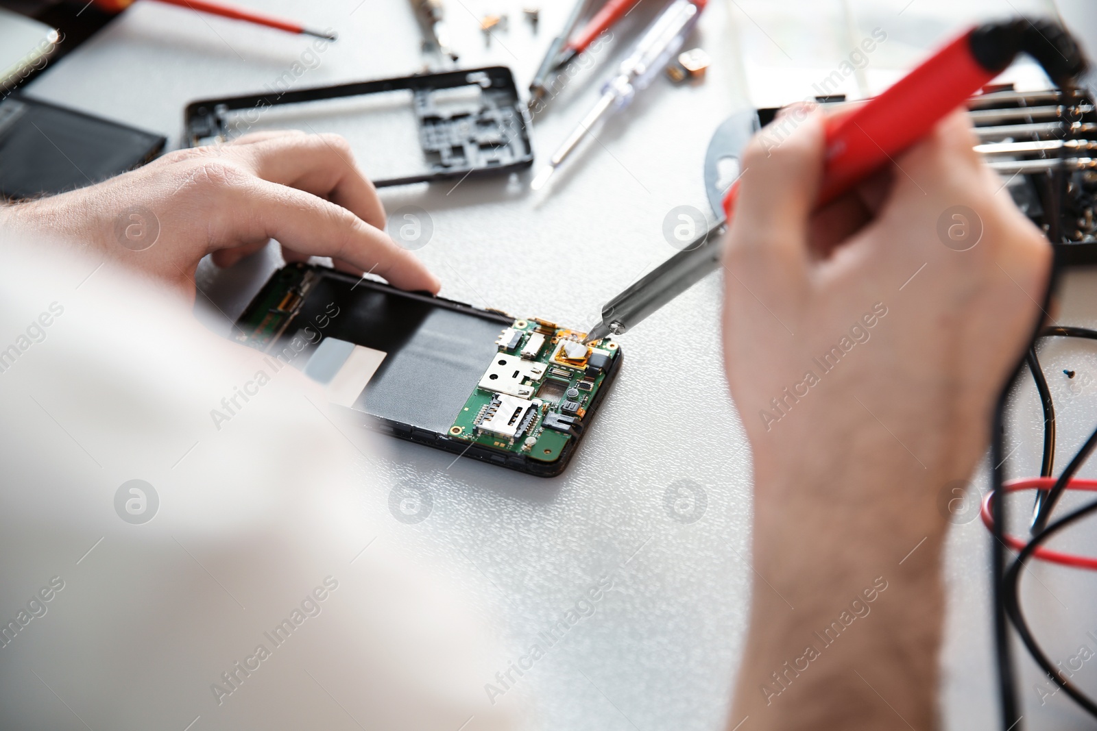 Photo of Technician repairing mobile phone at table, closeup