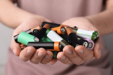 Image of Woman holding many used electric batteries in her hands, closeup