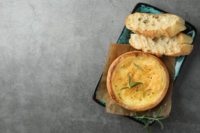 Plate with tasty baked brie cheese, bread and rosemary on grey table, top view. Space for text