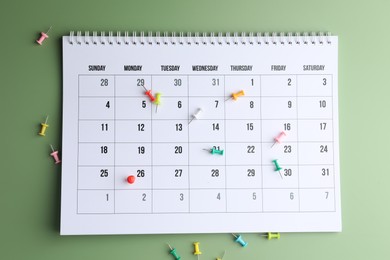 Photo of Timetable. Calendar and drawing pins on green background, top view