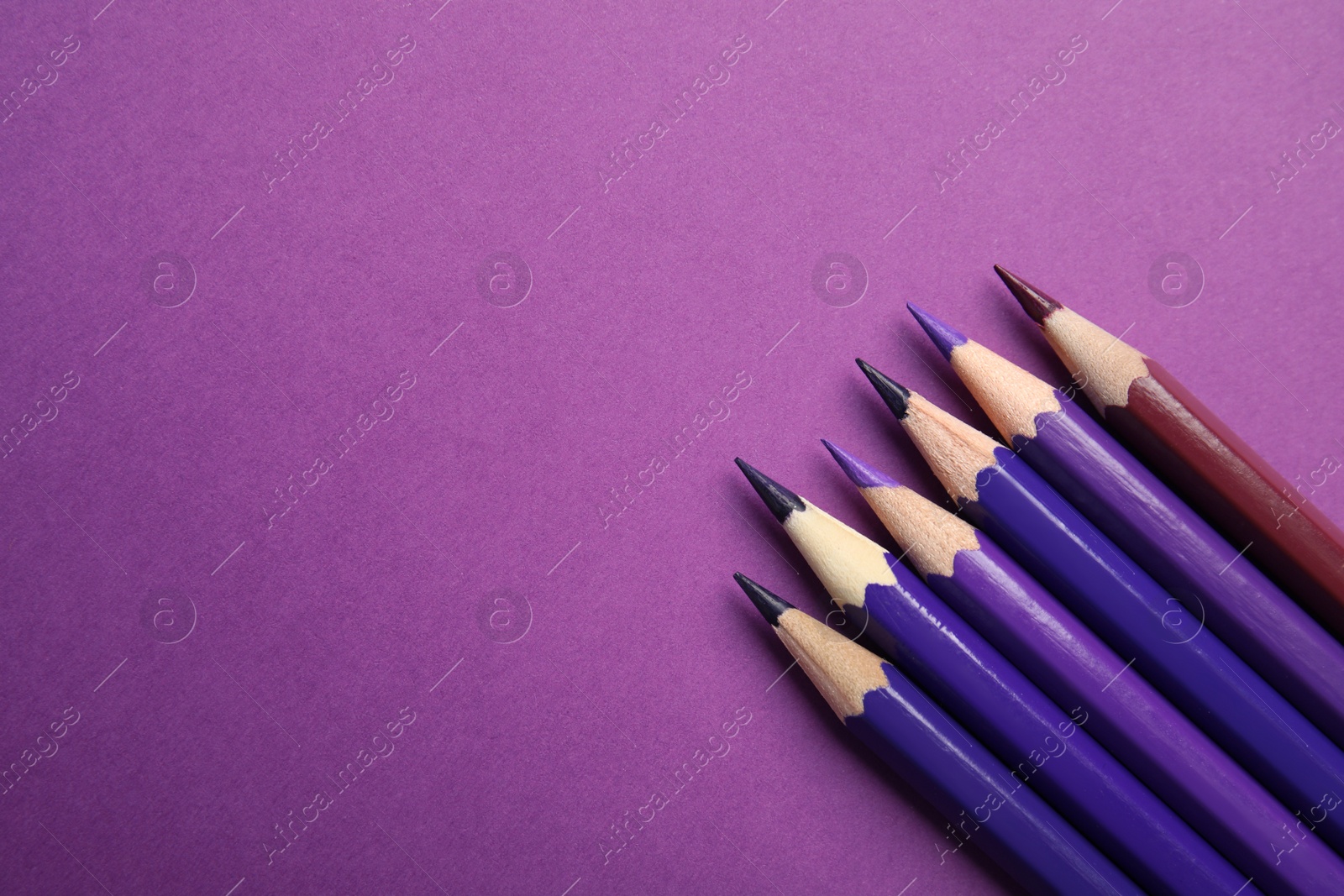 Photo of Flat lay composition with color pencils on purple background. Space for text