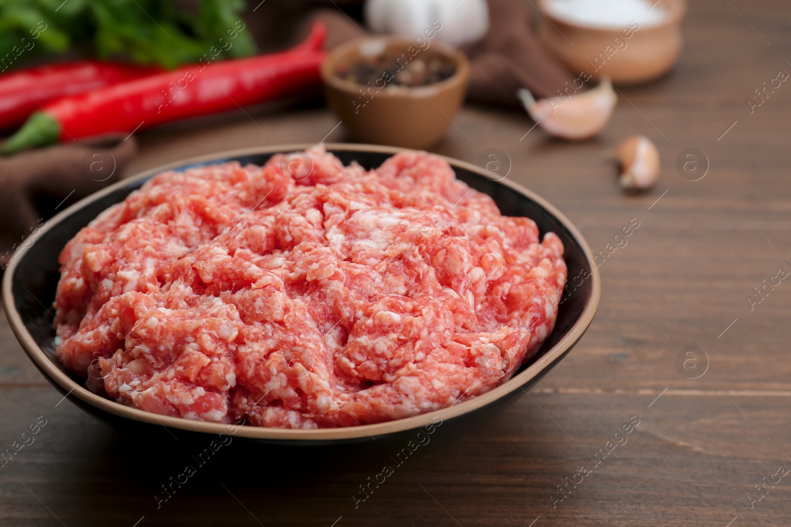 Photo of Bowl with raw fresh minced meat on wooden table, closeup