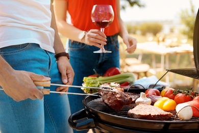 Young couple having barbecue with modern grill outdoors