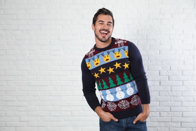 Portrait of happy man in Christmas sweater near white brick wall