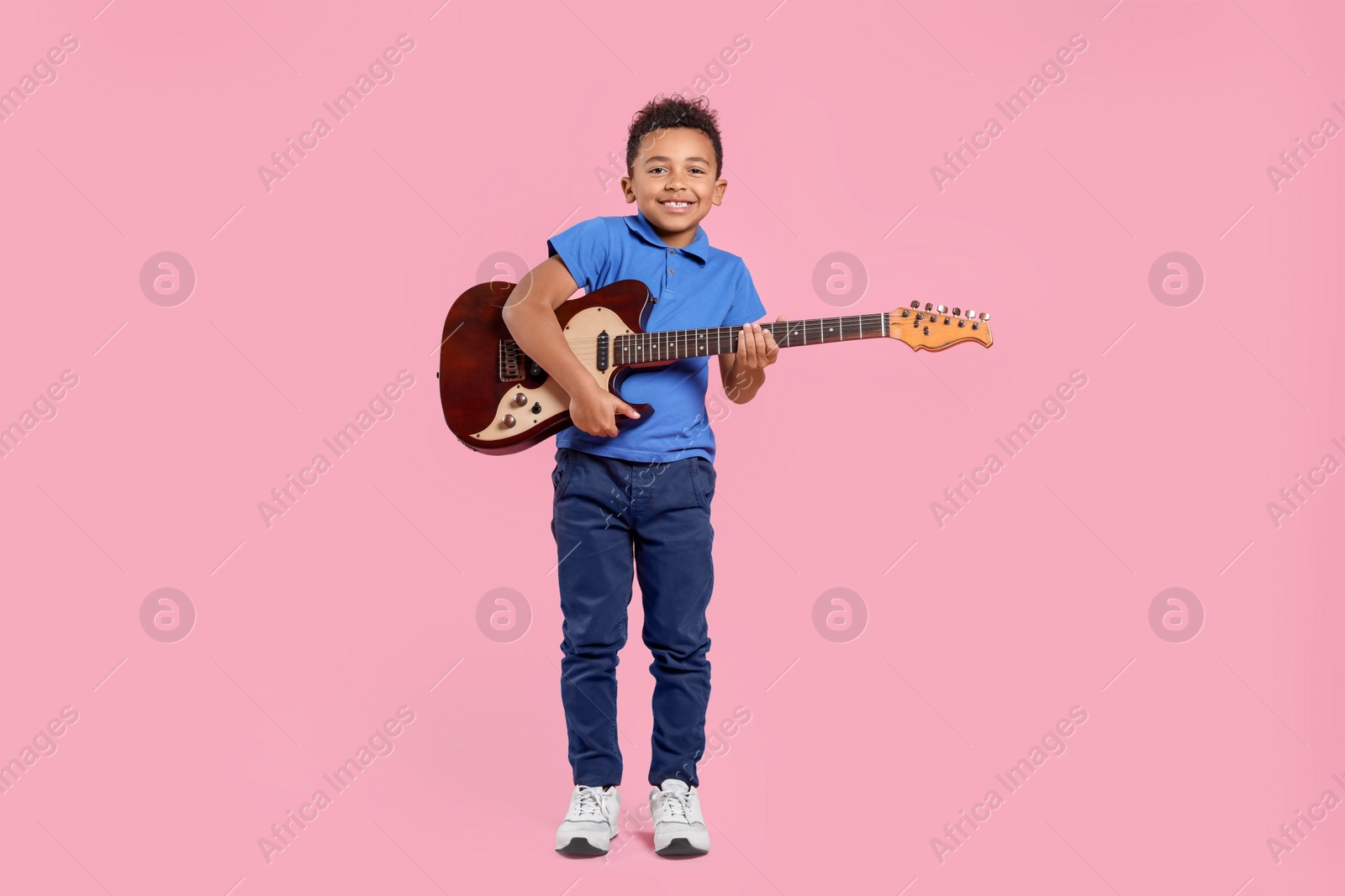 Photo of African-American boy with electric guitar on pink background