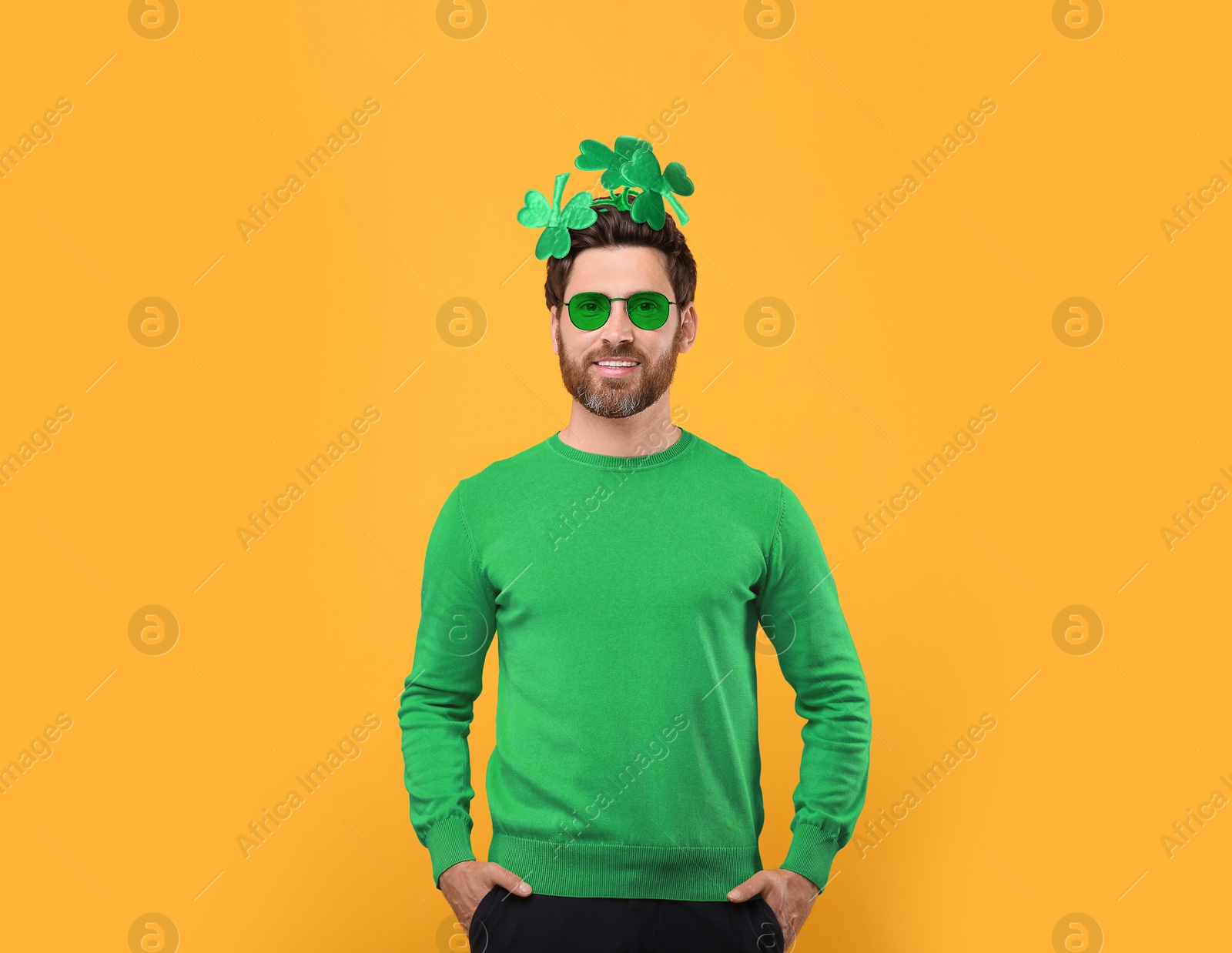 Image of St. Patrick's day party. Man with green sunglasses and clover headband on golden background