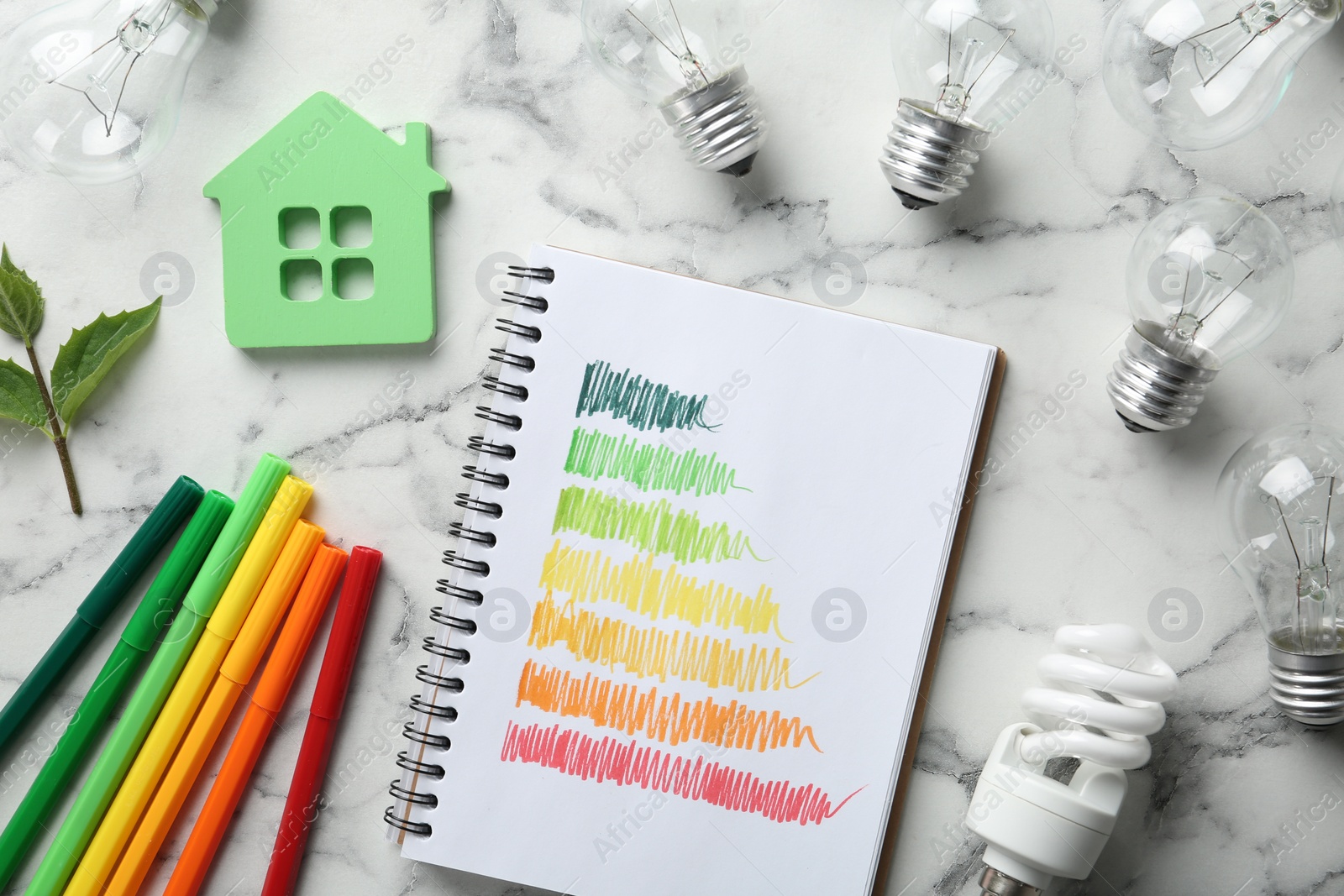 Photo of Flat lay composition with energy efficiency rating chart, colorful markers, house figure and light bulbs on white marble background