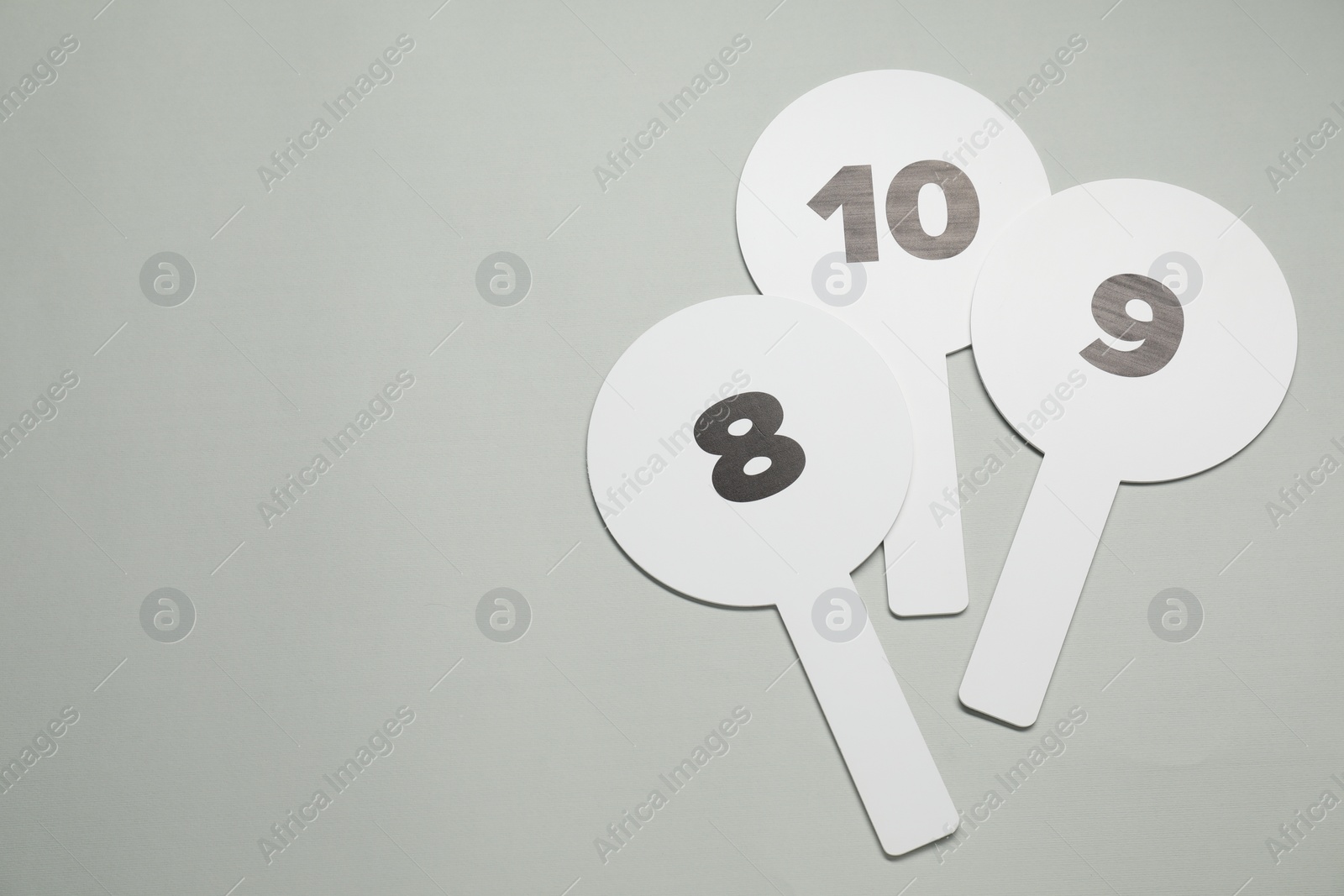 Photo of Auction paddles with numbers on light grey background, flat lay. Space for text