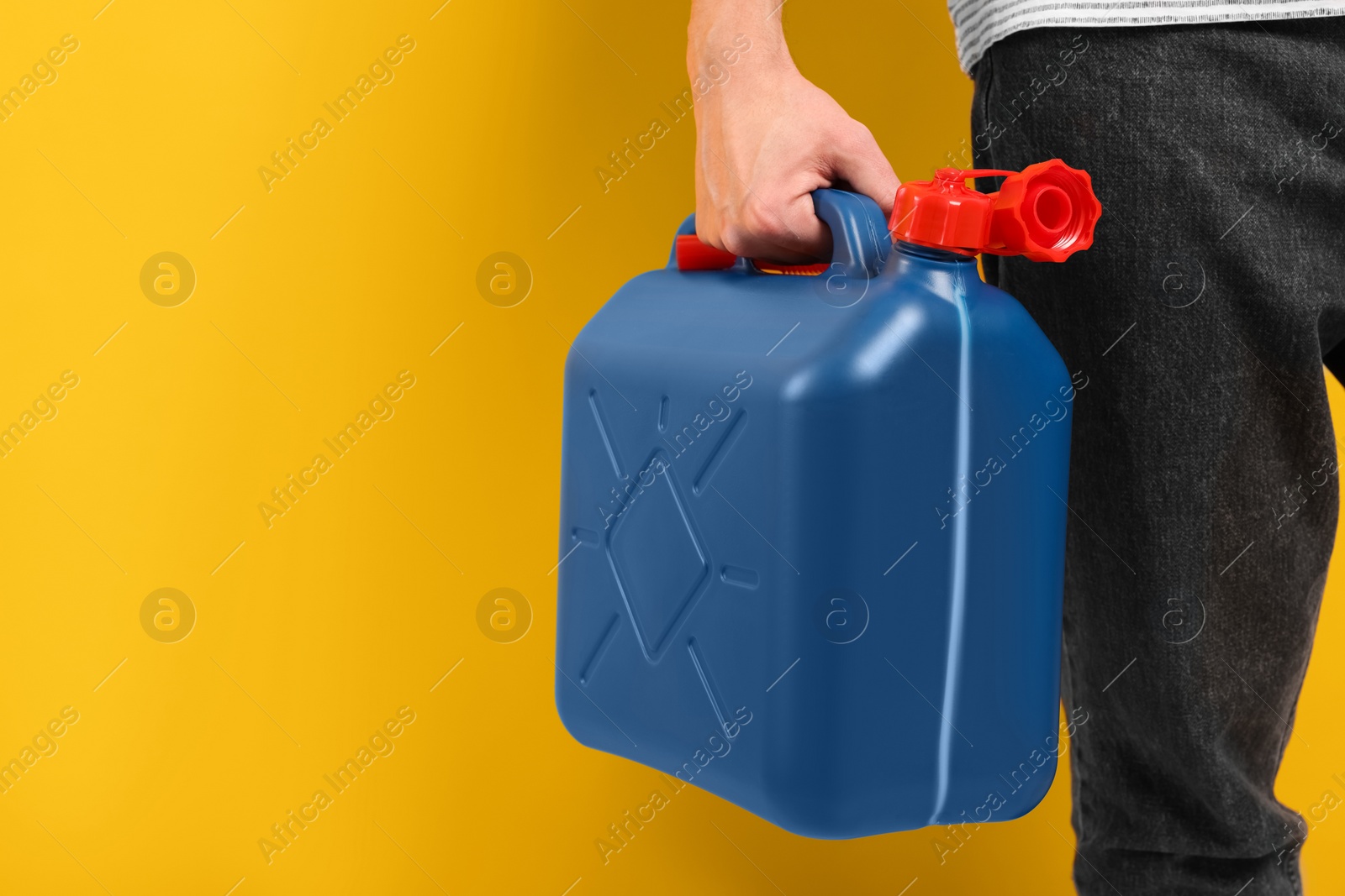 Photo of Man holding blue canister on orange background, closeup. Space for text