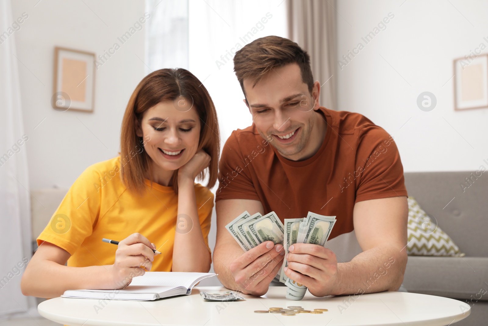 Photo of Couple counting money at table in living room