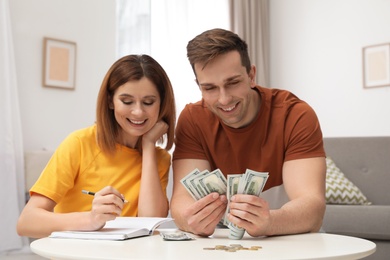 Photo of Couple counting money at table in living room