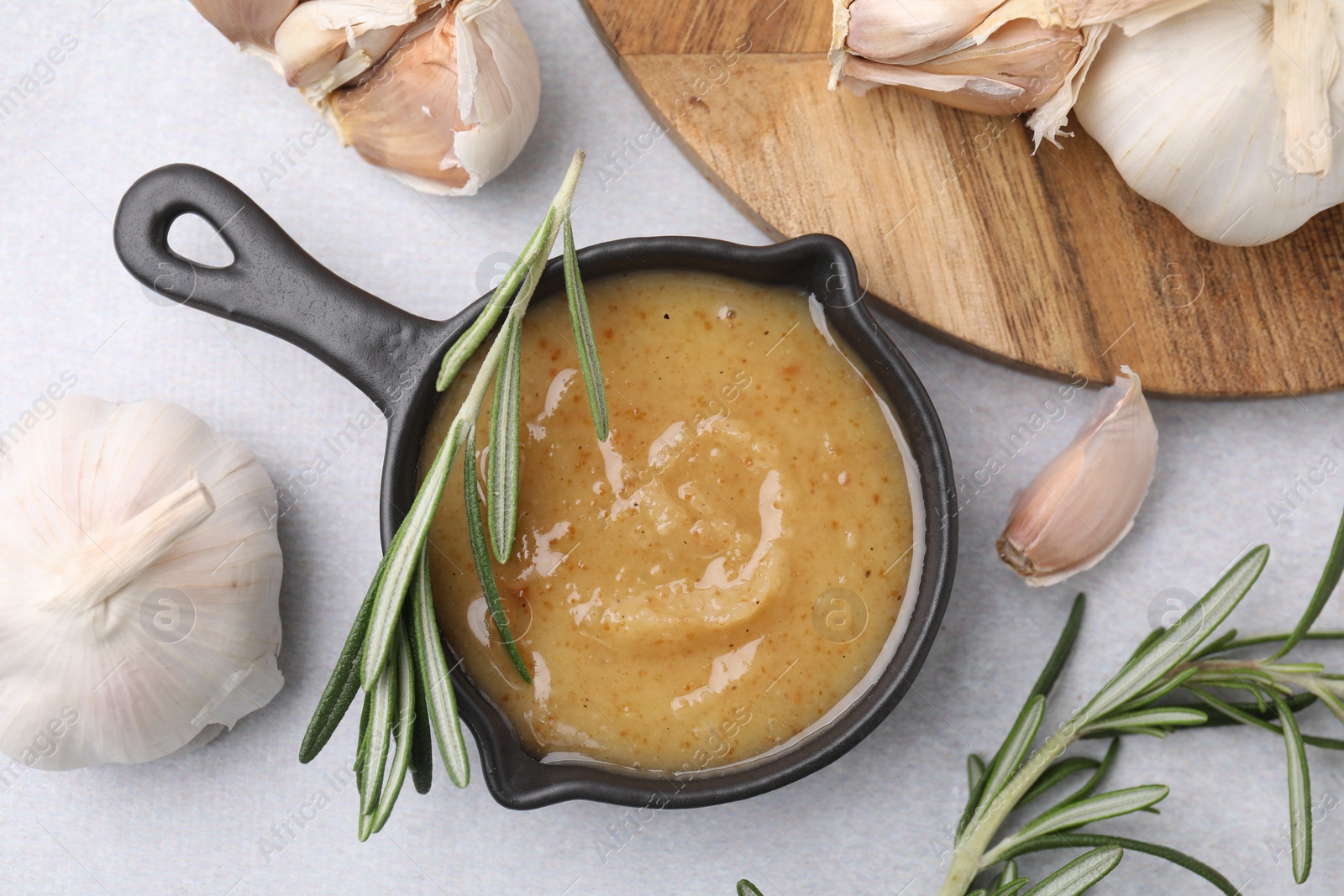 Photo of Delicious turkey gravy, rosemary and garlic on light grey table, flat lay