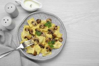 Delicious ravioli with mushrooms and sauce served on white wooden table, flat lay. Space for text