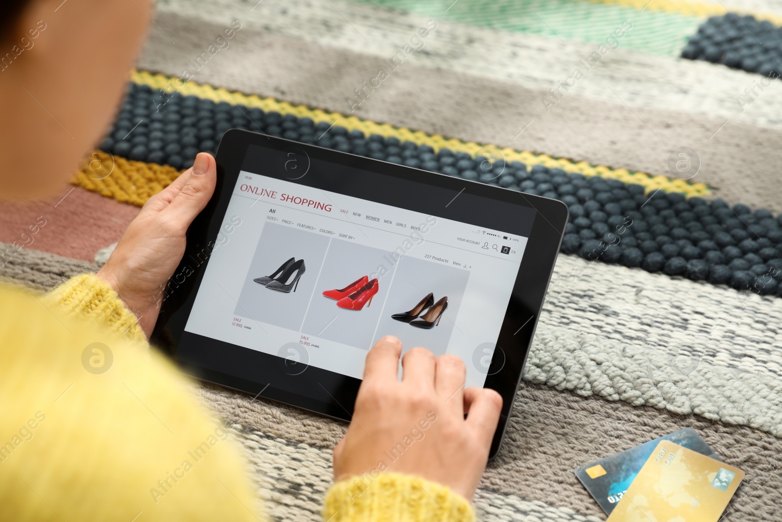 Photo of Woman with credit cards using tablet for online shopping on carpet, closeup