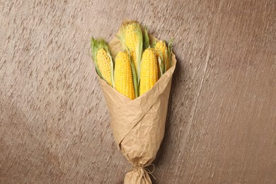 Photo of Corn cobs wrapped in parchment on table, top view