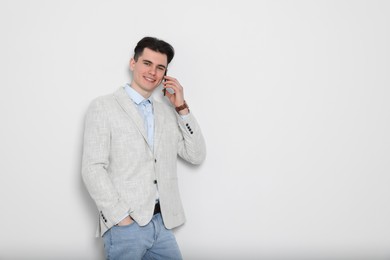 Photo of Handsome young man talking on phone against white background, space for text