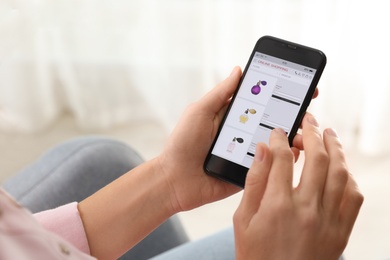 Photo of Woman using smartphone for online shopping indoors, closeup