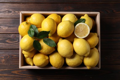 Photo of Fresh lemons in crate on wooden table, top view