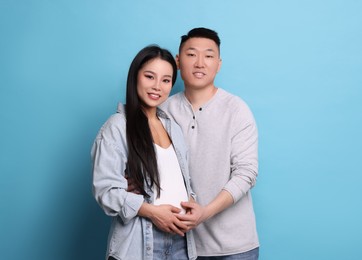 Photo of Pregnant woman and her husband on light blue background, space for text