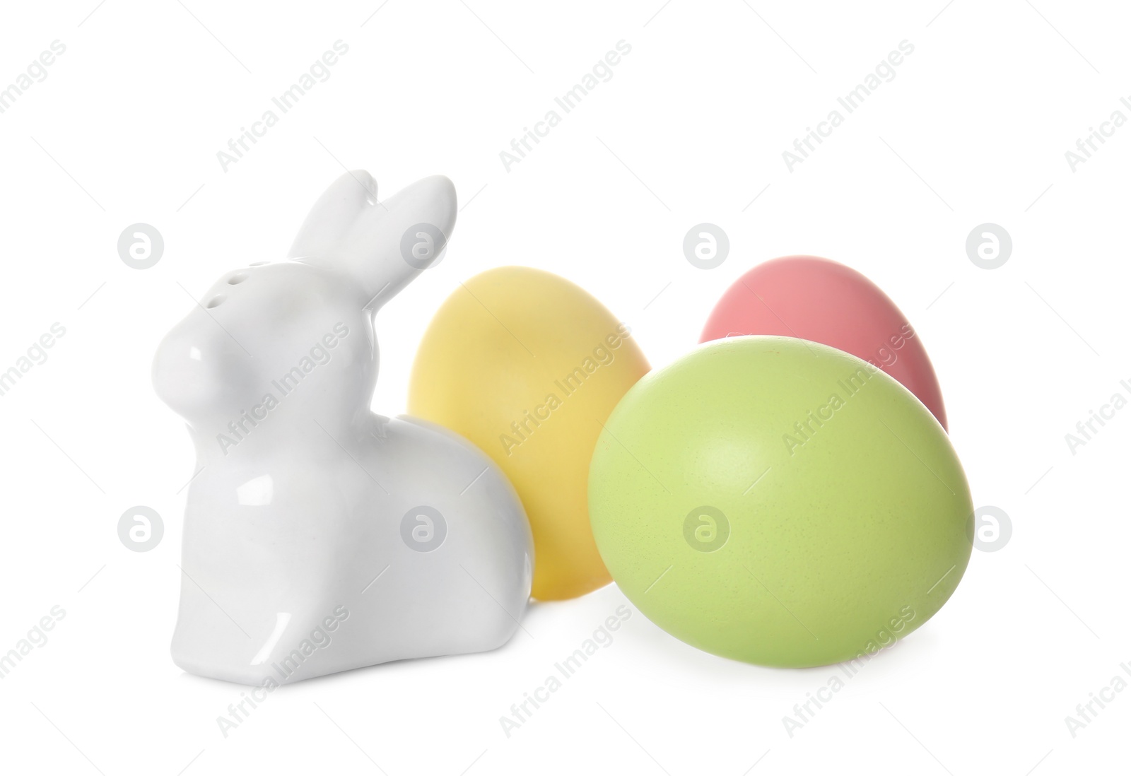 Photo of Cute ceramic Easter bunny and dyed eggs on white background