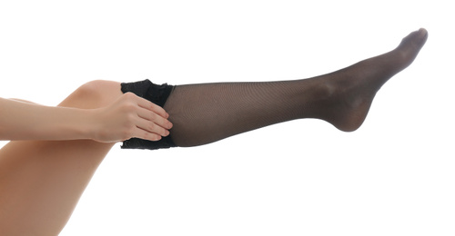 Photo of Young woman putting on stocking against white background, closeup