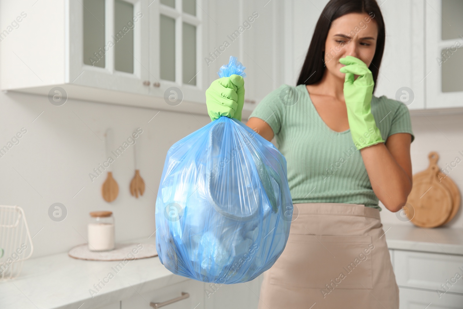 Photo of Woman holding full garbage bag at home, focus on hand