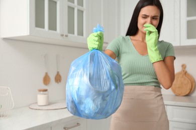 Woman holding full garbage bag at home, focus on hand