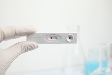 Photo of Doctor holding disposable express test for hepatitis indoors, closeup
