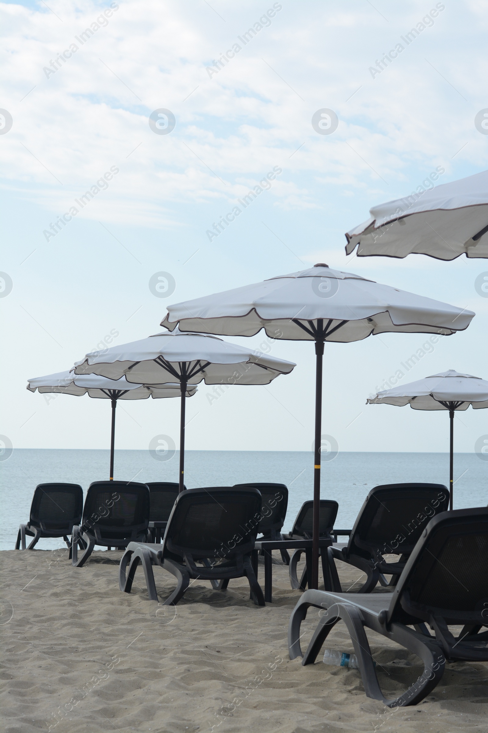 Photo of Many beautiful white umbrellas and black sunbeds on beach