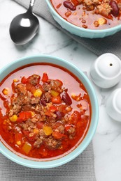 Photo of Tasty chili con carne on white marble table, flat lay