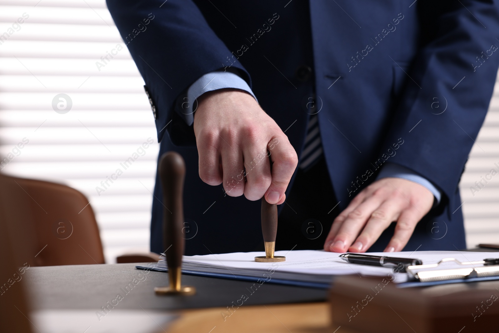 Photo of Notary stamping document at table in office, closeup