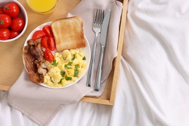 Photo of Good morning. Tray with tasty breakfast on bed, top view