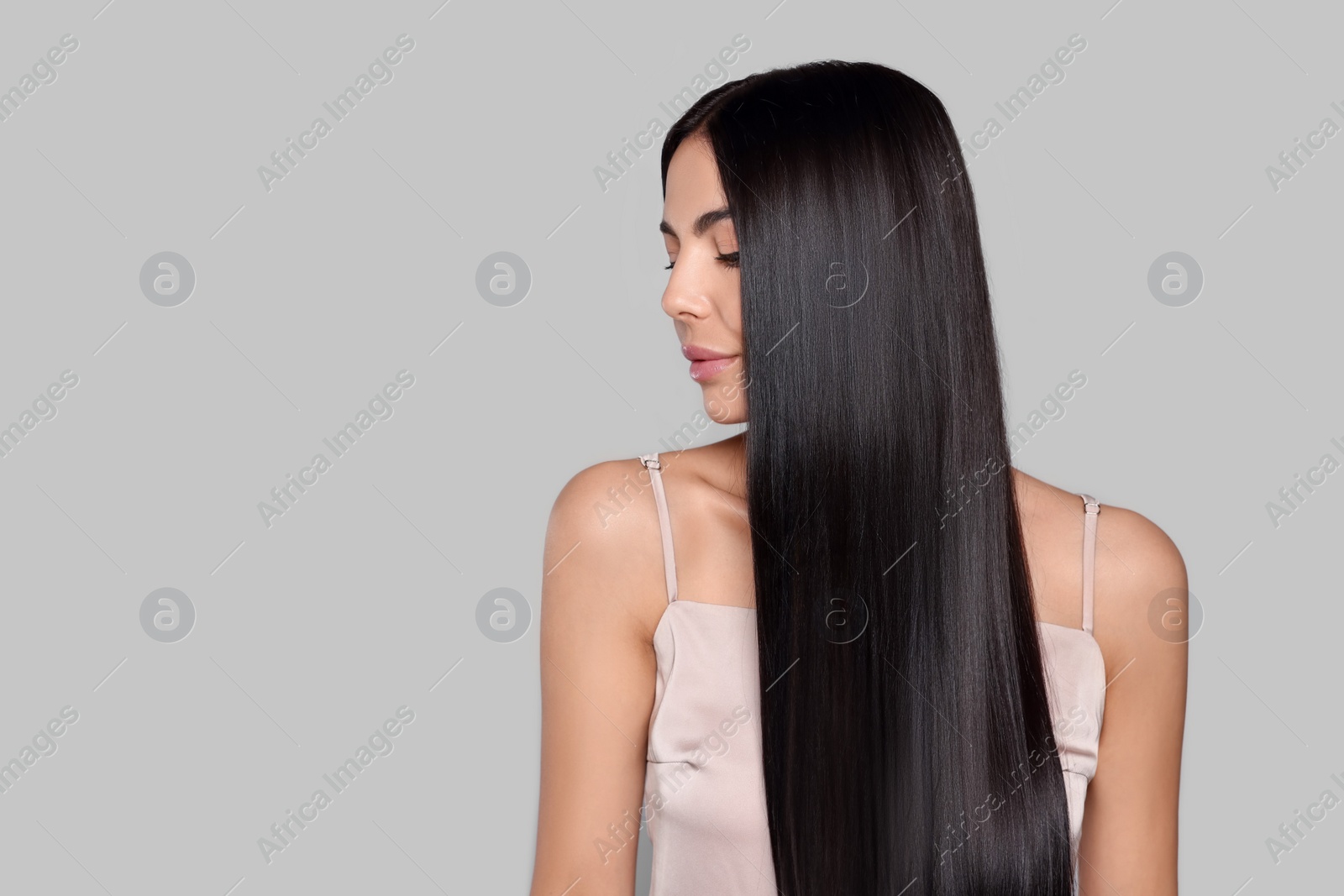 Photo of Portrait of beautiful young woman with healthy strong hair on light grey background, space for text