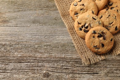 Photo of Delicious chocolate chip cookies on wooden table, top view. Space for text