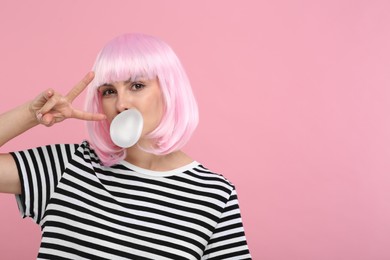 Photo of Beautiful woman blowing bubble gum and gesturing on pink background, space for text