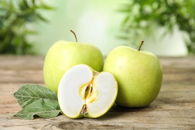 Photo of Fresh ripe green apples on wooden table against blurred background