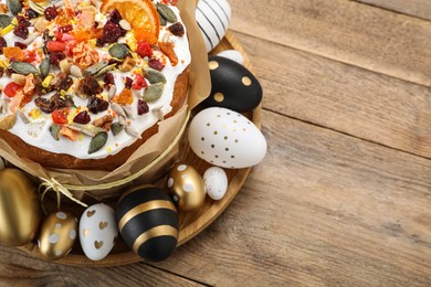 Traditional Easter cake with dried fruits and painted eggs on wooden table, above view. Space for text
