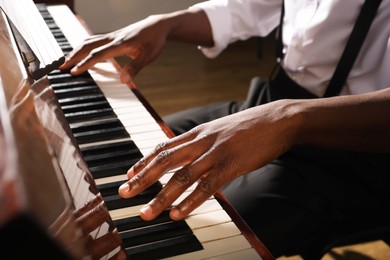 Photo of African-American man playing piano indoors, closeup. Talented musician
