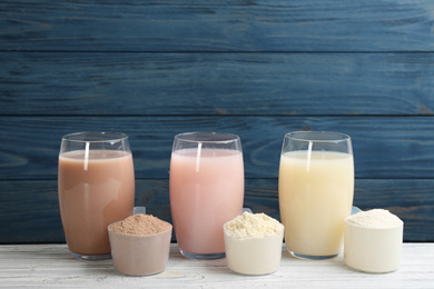 Photo of Protein shakes and powder on white wooden table