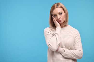 Sad woman on light blue background. Space for text