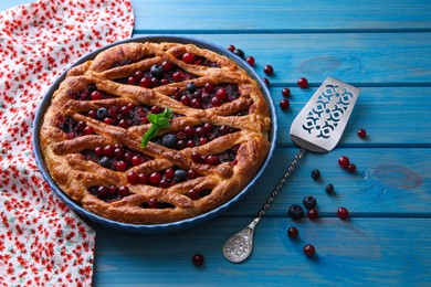 Photo of Delicious currant pie with fresh berries and spatula on blue wooden table