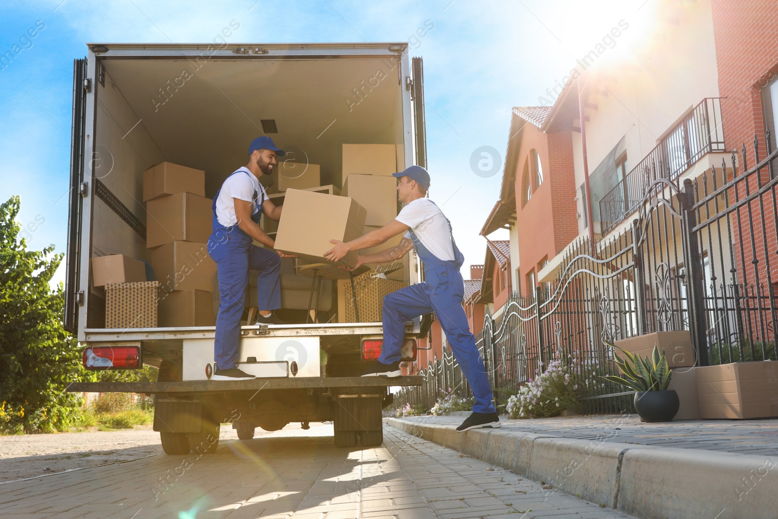 Photo of Workers unloading boxes from van outdoors. Moving service