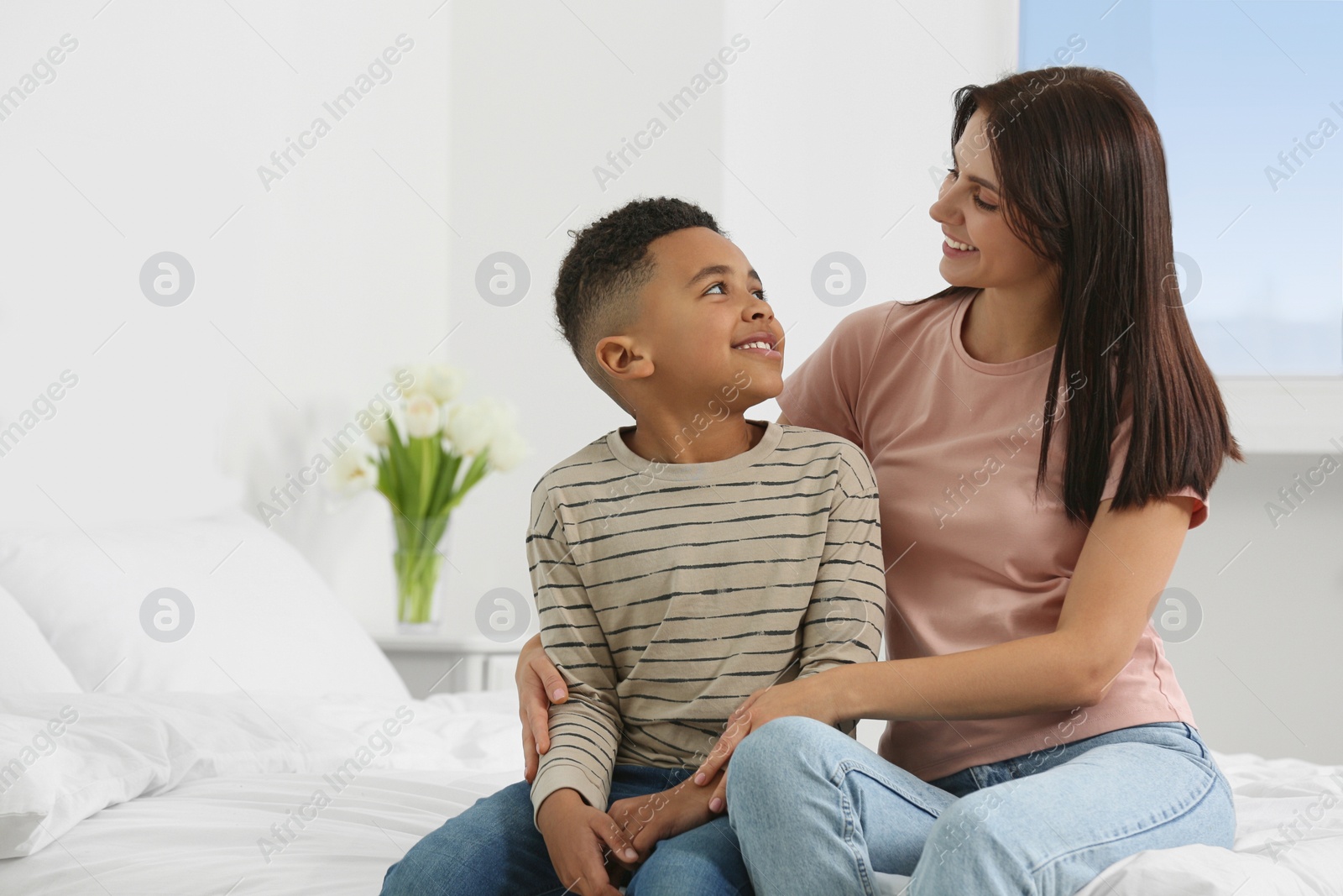 Photo of Mother with her African American son on bed at home. International family