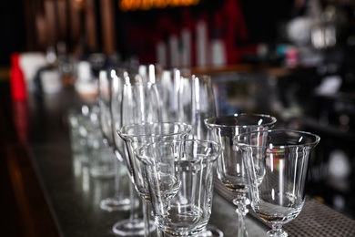 Photo of Different empty clean glasses on counter in bar