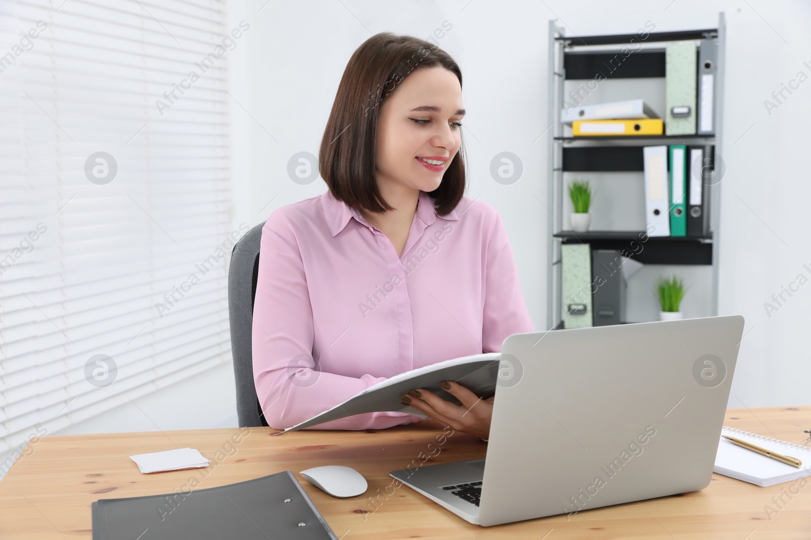 Photo of Happy young intern working at table in modern office