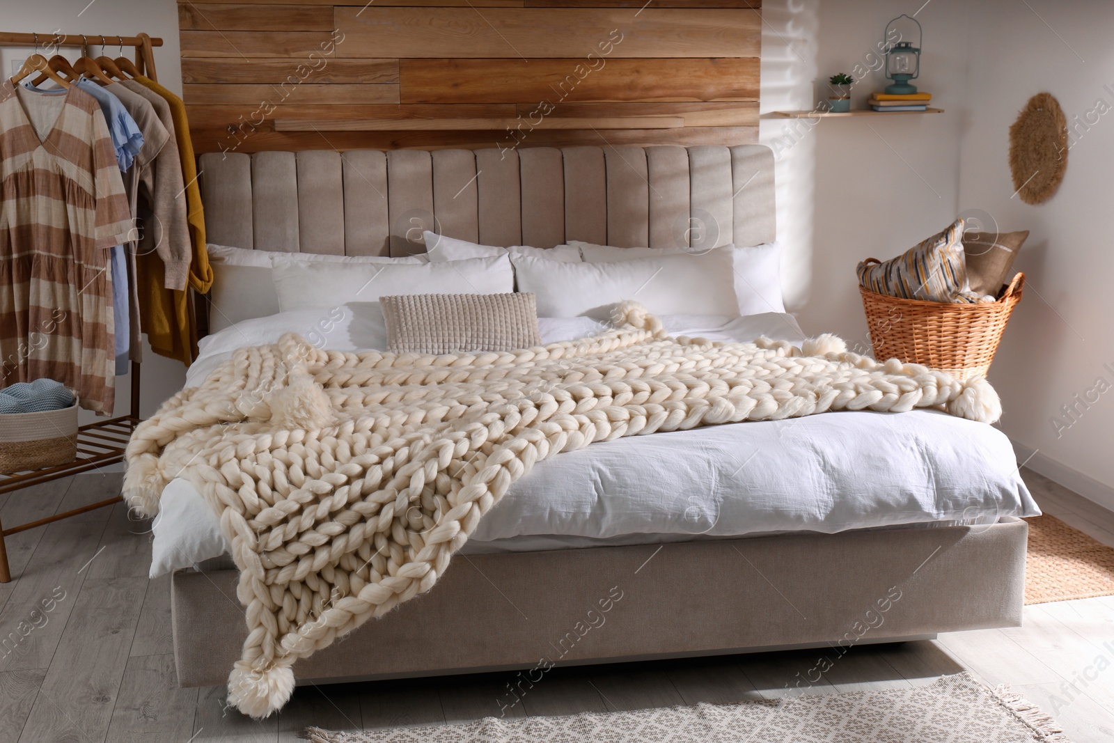 Photo of Bed with white knitted plaid in room. Interior design